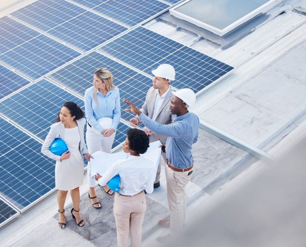 Solar energy, teamwork or engineering team on roof by solar panels for electricity technology innov.